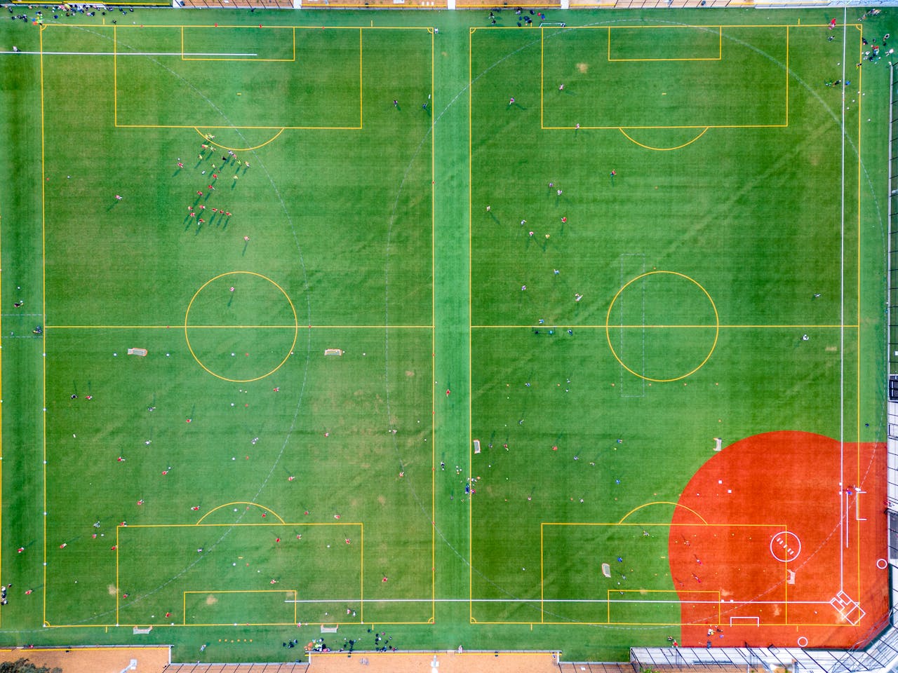 Aerial shot of a vibrant green soccer field with players visible, showcasing sports activity.