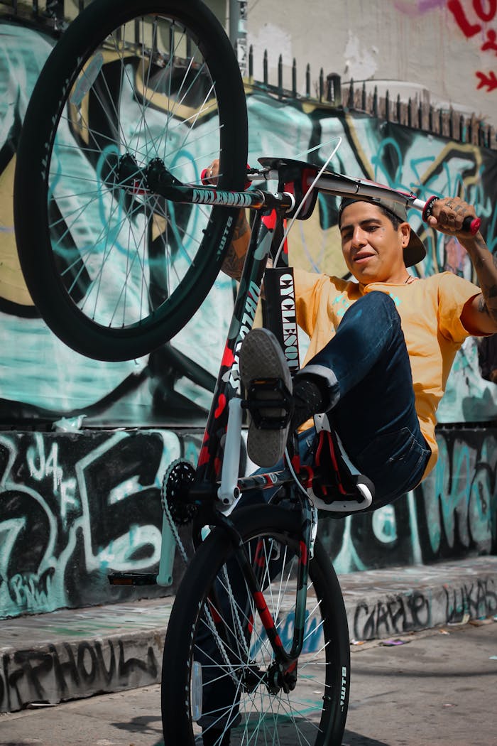 Energetic BMX cyclist performing tricks against a graffiti-covered urban backdrop.
